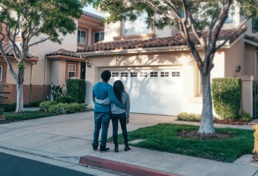 a couple standing before a house